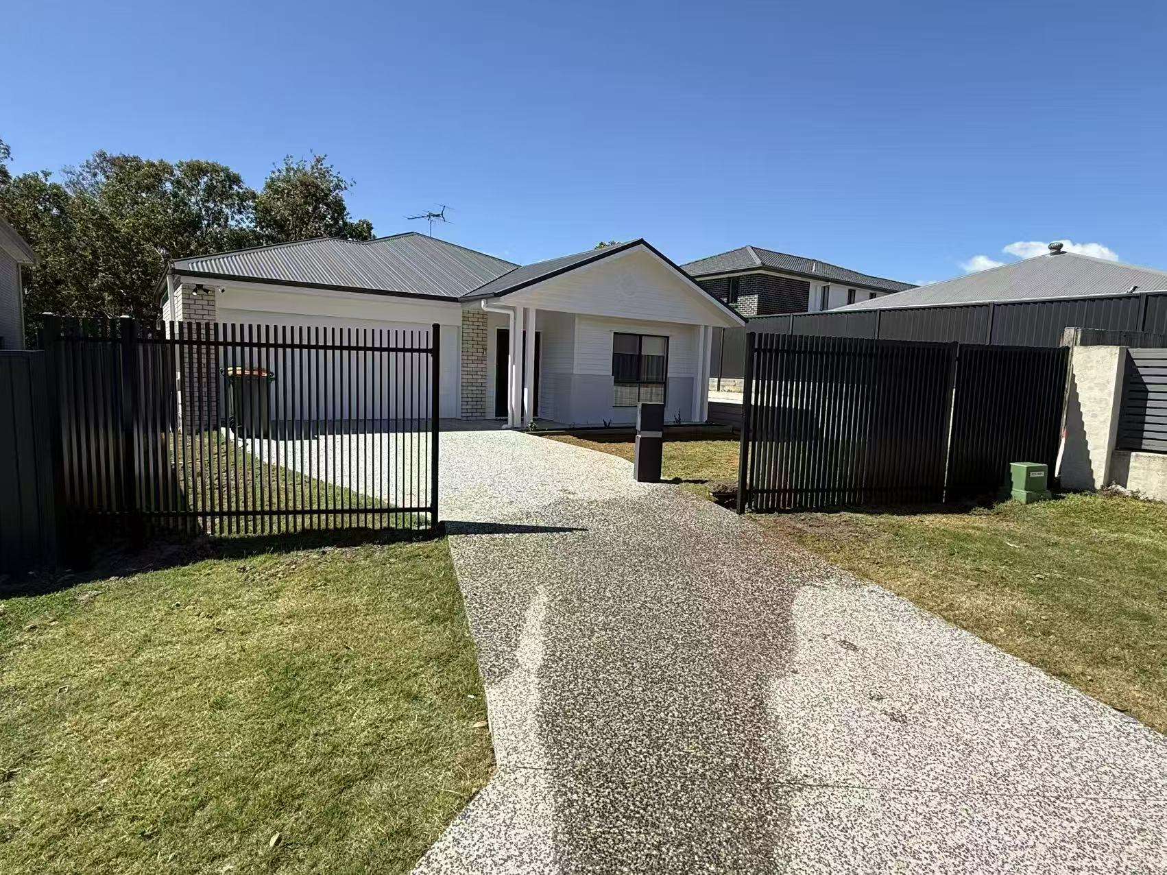 Black aluminium front fence with an open driveway gate and letterbox at a single storey Brisbane home