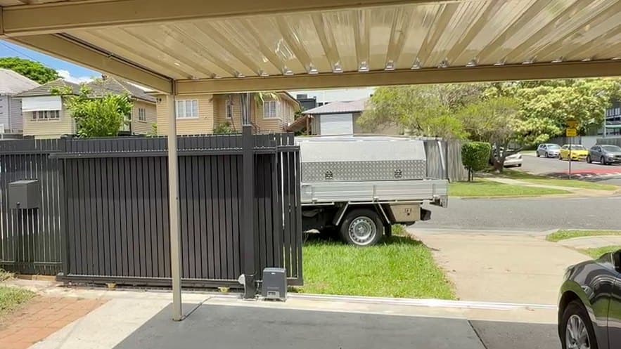 The same sliding gate open, telescoped to one side, with the street beyond