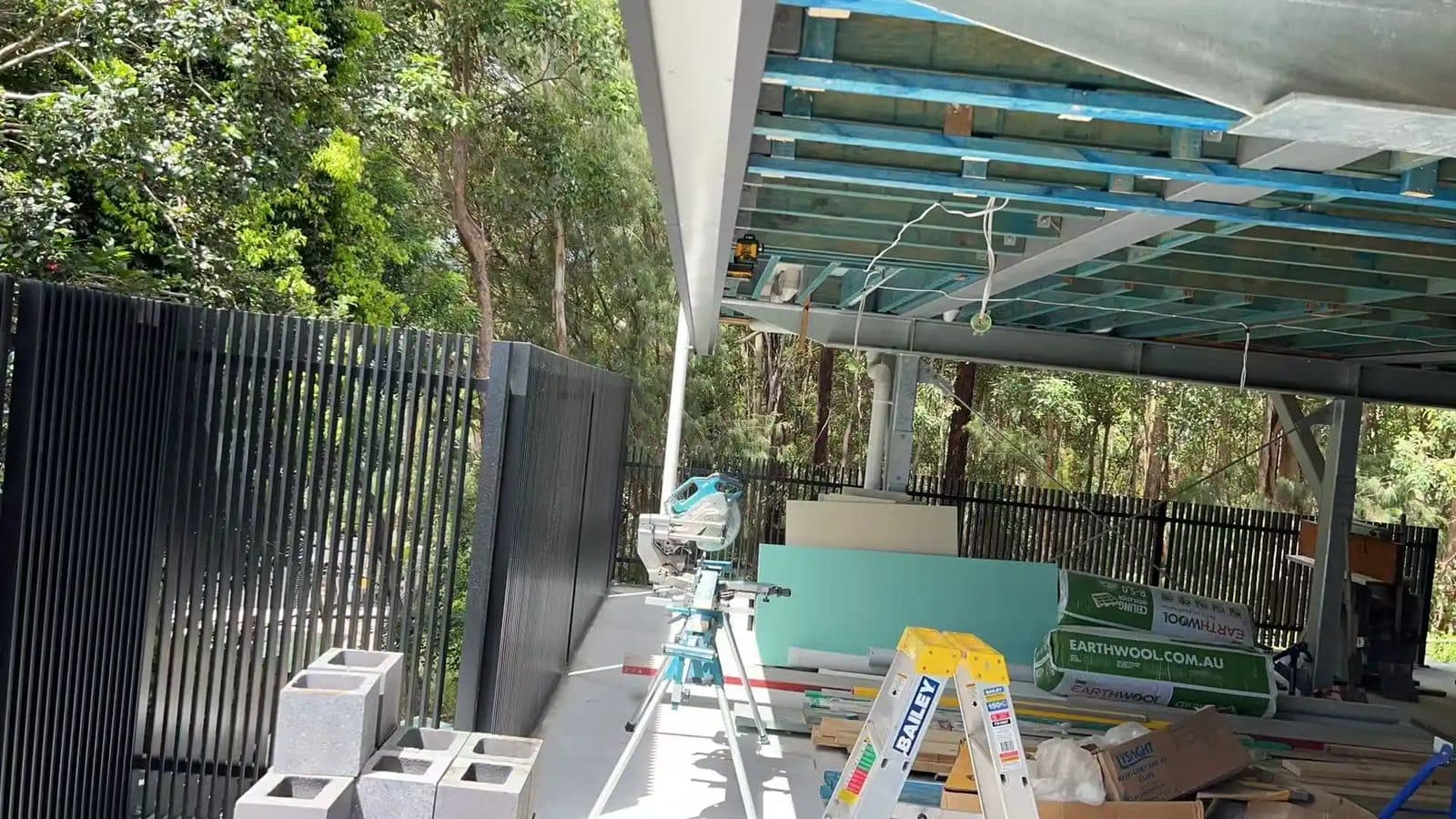 Black aluminium vertical batten fence beside a carport