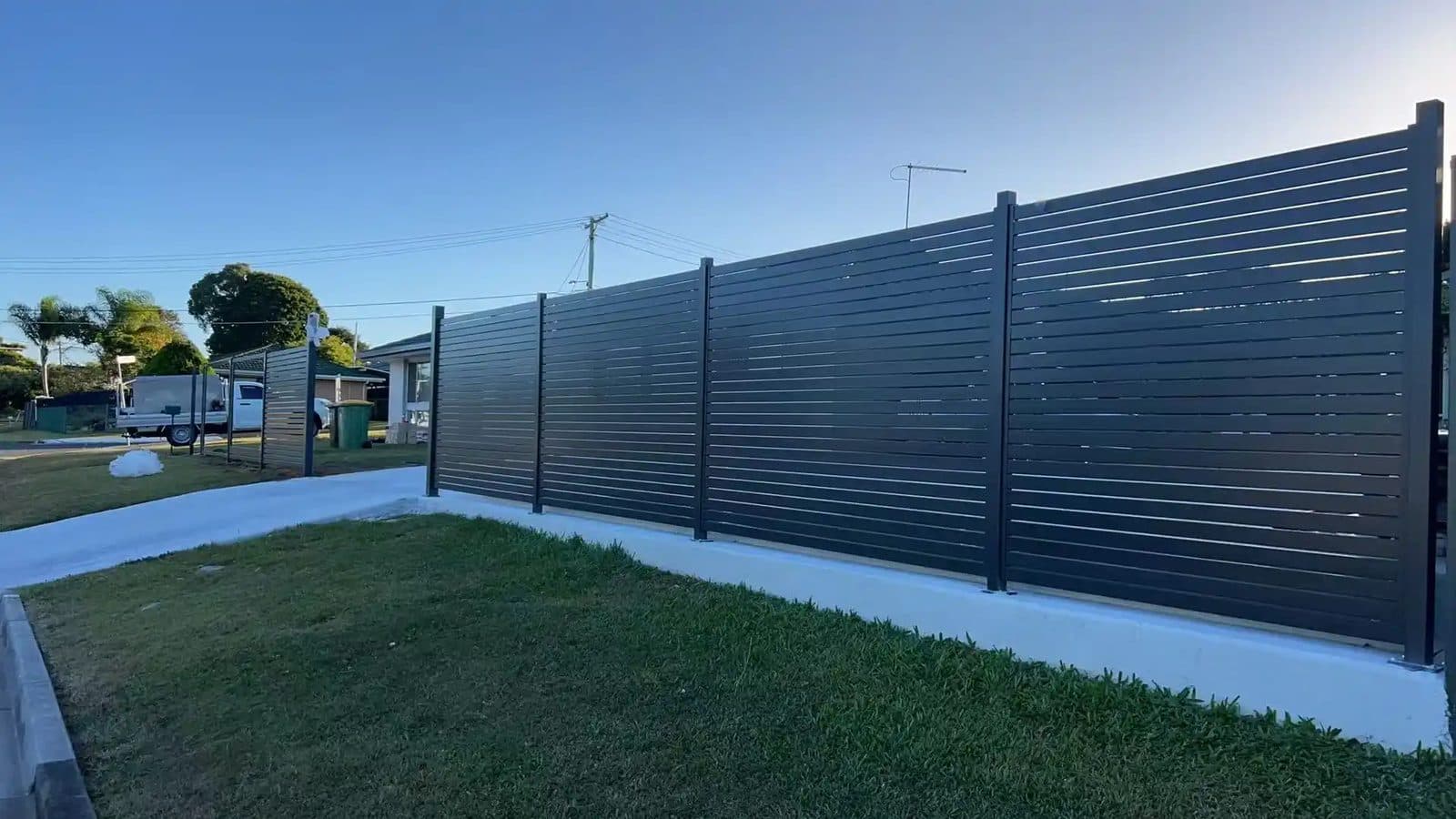 Charcoal horizontal slat aluminium fence along a front yard