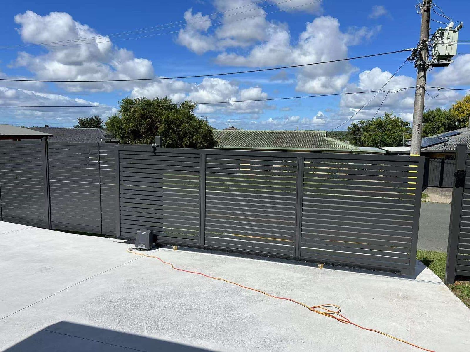 Monument aluminium horizontal slat sliding driveway gate and fence across a new concrete driveway
