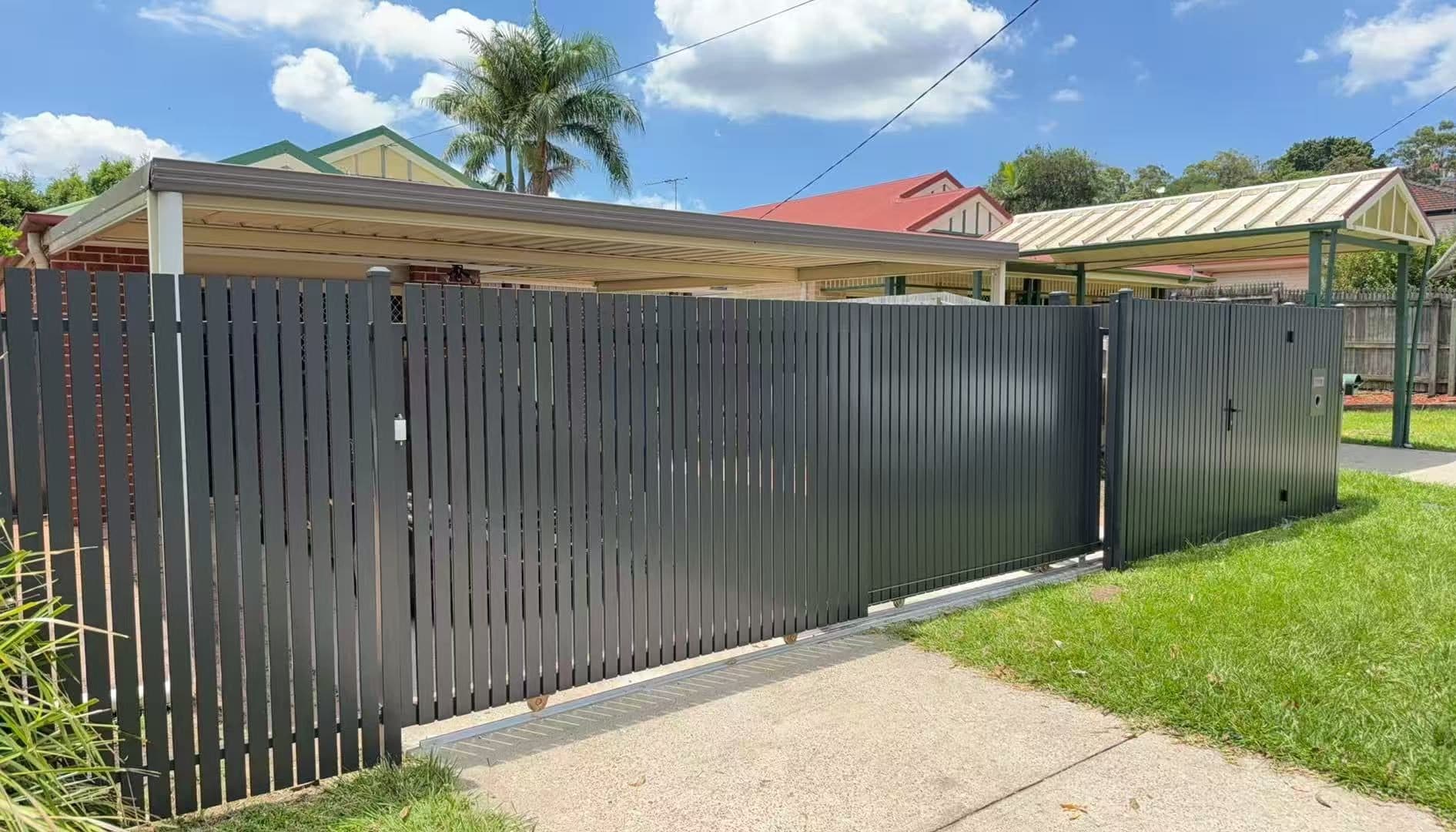 Monument aluminium vertical picket sliding driveway gate, fence and pedestrian gate in front of a carport