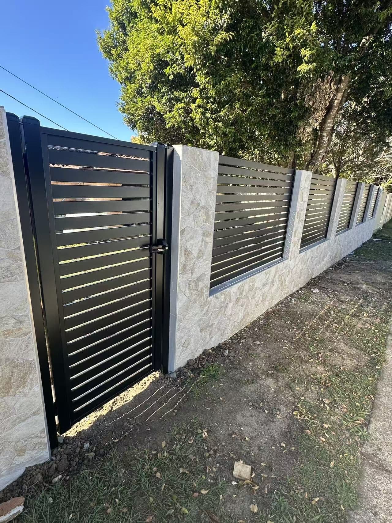Black aluminium horizontal slat pedestrian gate and infill panels in a stone-clad front wall